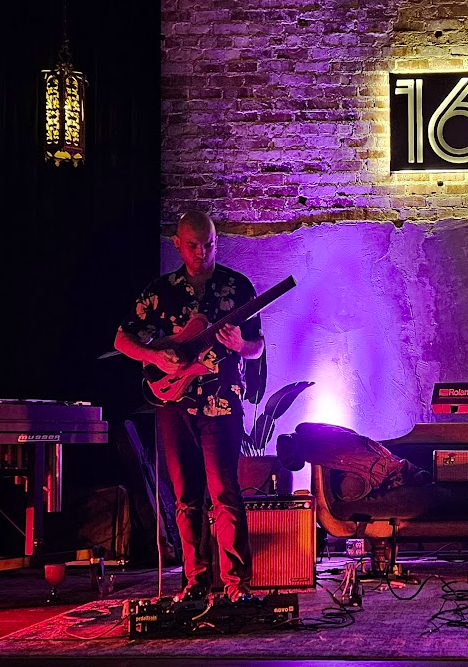 Ben Meyer performing beneath purple stage lights