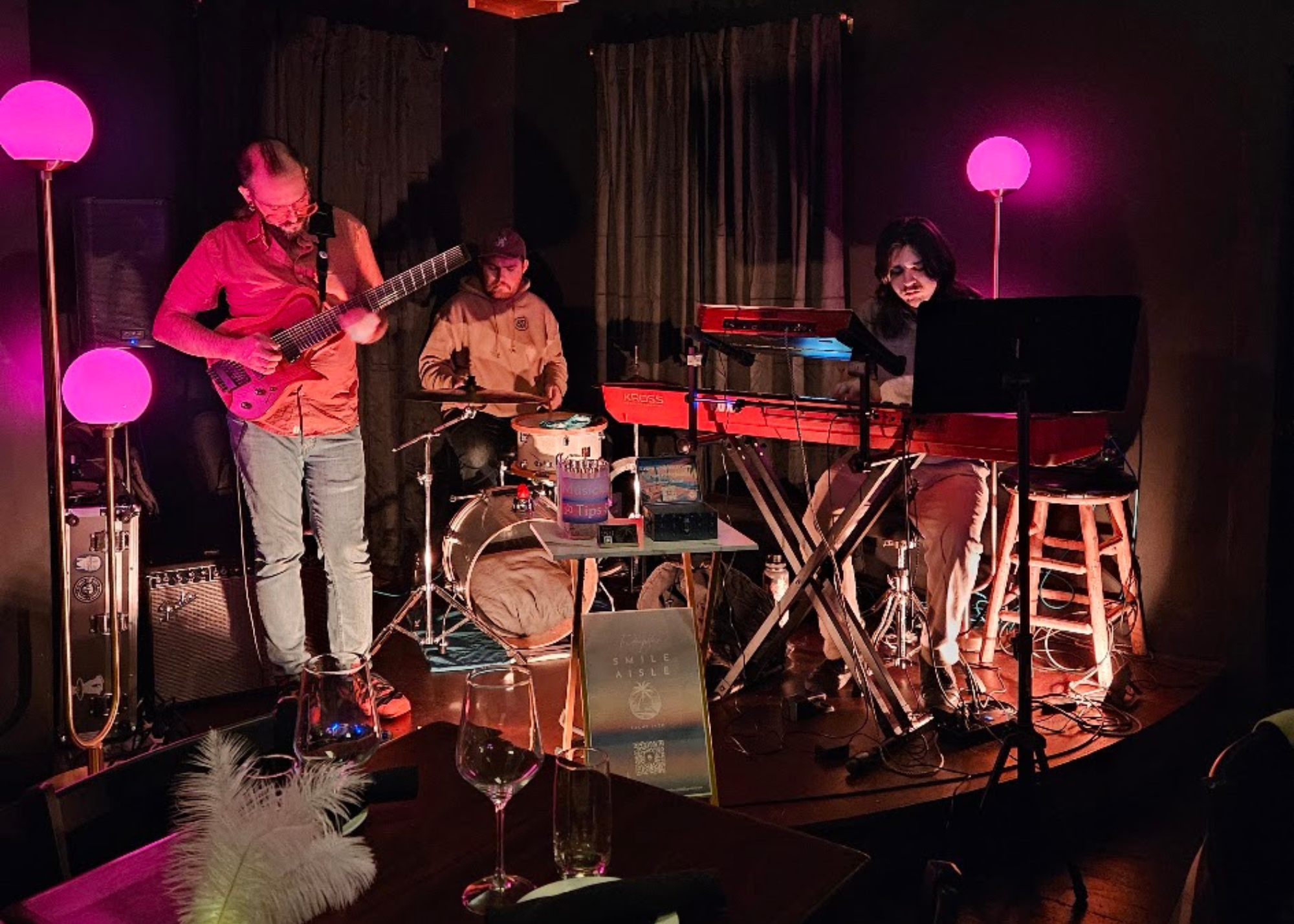 Smile Aisle trio performing under pink stage lighting