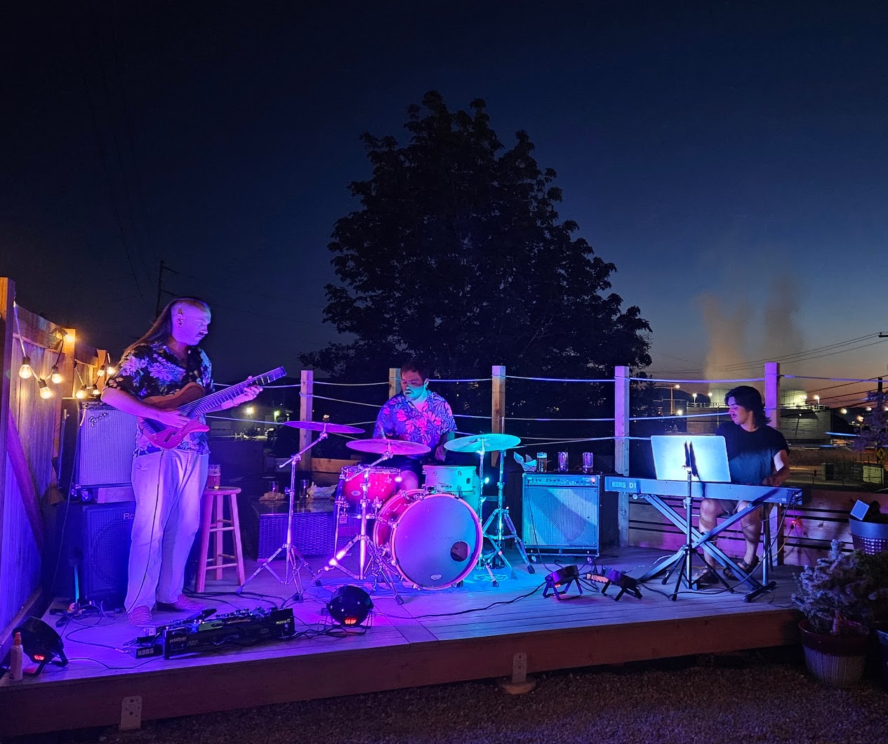 Smile Aisle trio performing on a rooftop at night