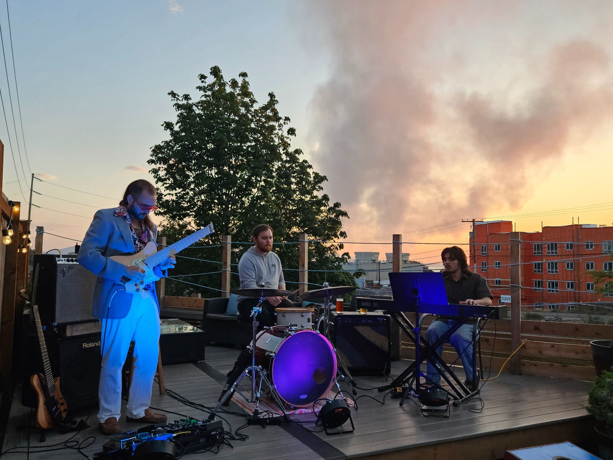 Smile Aisle trio performing on a rooftop at sunset